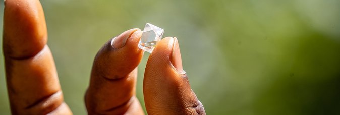A hand holding a rough diamond